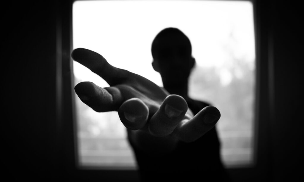 A man in shadow, extending hand for help